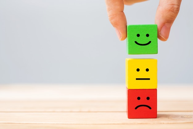 Hand holding emotion face symbol wooden blocks