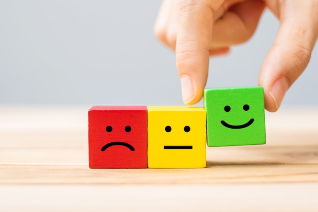 hand holding emotion face symbol wooden blocks