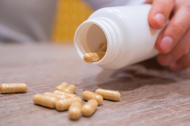 Hand holding and emptying a bottle of pills on the table