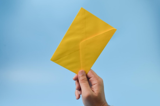 Hand holding envelope isolated on a blue background