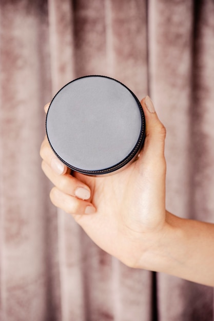 Photo hand holding face cream jar mockup