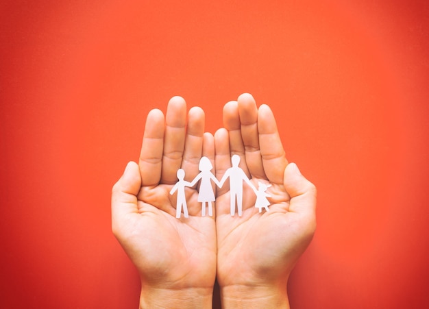 Hand holding family paper cut on red surface