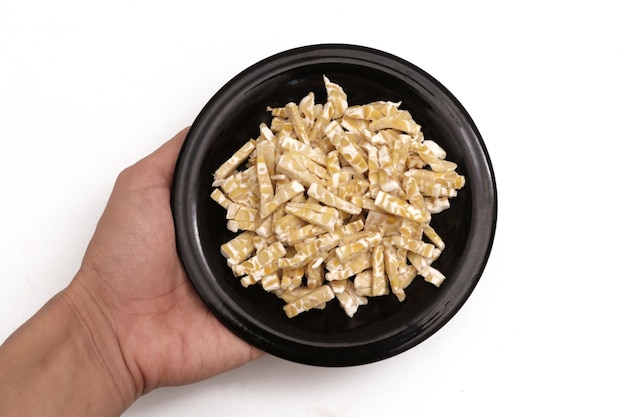 hand holding fermented soybeans that have been cut into small pieces on a black plate