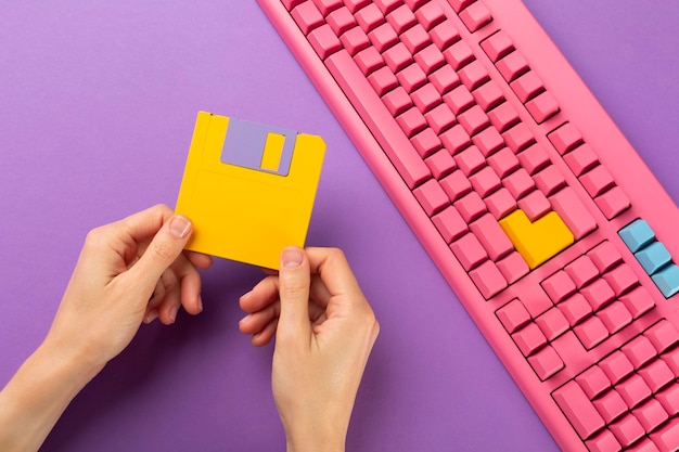 Hand holding floppy disk on color keyboard background technology concept