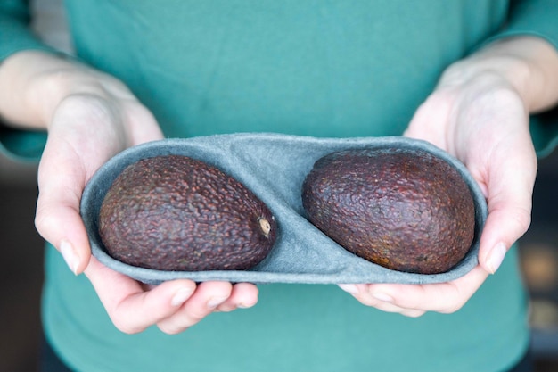 Hand holding fresh avocado closeup the process of opening an avocado to replace butter on sandwiches