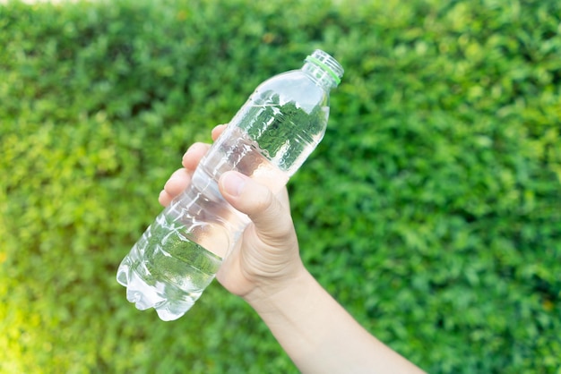 Hand holding fresh a bottle of drinking water on green leaf background concept natural water for the best health for life