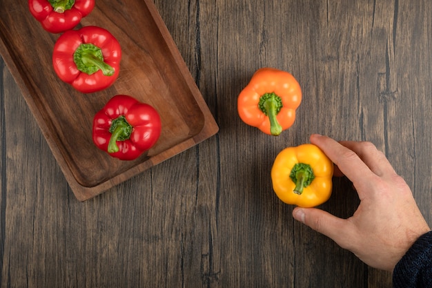 Hand holding fresh red bell pepper on wooden surface