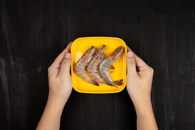 Hand holding Fresh Shrimp on black background.