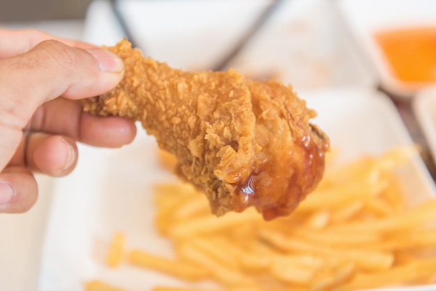 Photo hand holding fried chicken and eating in the restaurant

