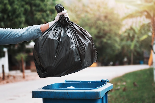 Hand holding garbage black bag putting in to trash