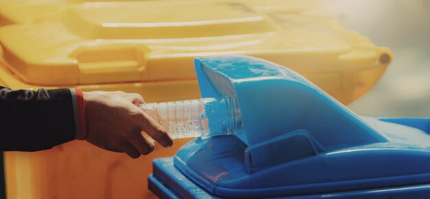 Hand holding garbage bottle plastic putting into trash for cleaning