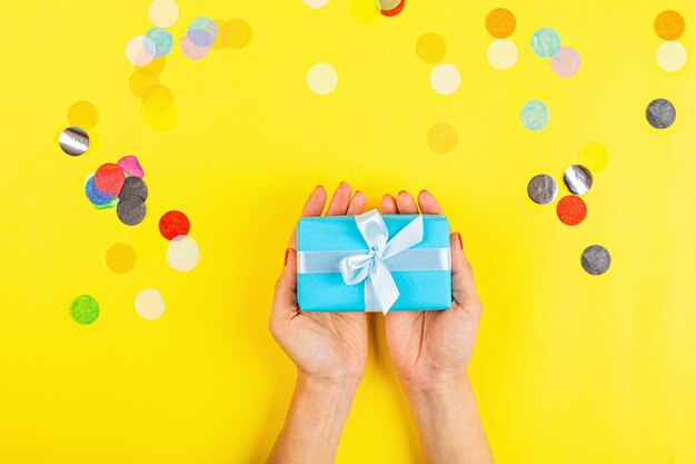 Hand holding gift box on yellow background