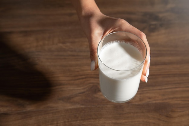 Hand holding a glass of milk on the table