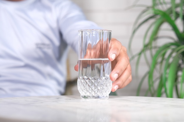 Рука, держащая стакан воды на белом фоне,