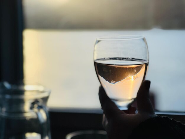 Hand holding a glass of wine at sunset