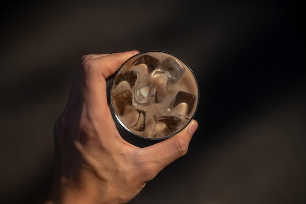 A hand holding a glass with ice on it