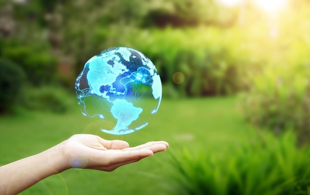 Hand holding a globe graphic on nature background, Renewable energy-based green businesses can