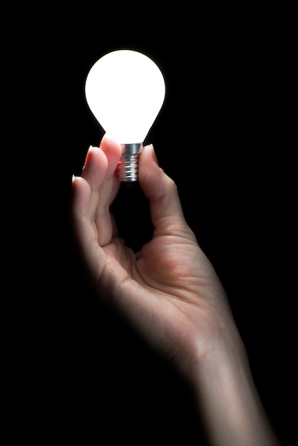 Photo hand holding a glowing light bulb