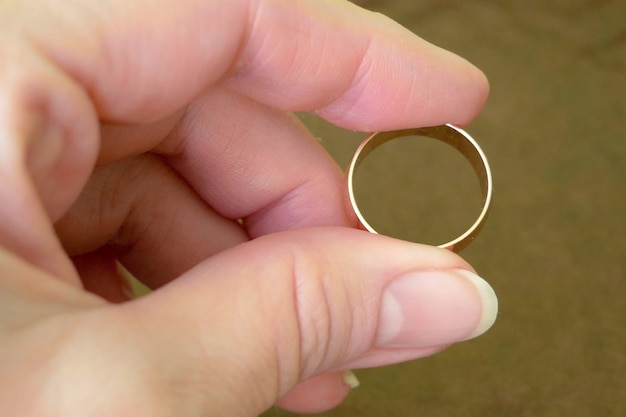 사진 갈색 바탕에 황금 결혼 반지를 들고 있는 손