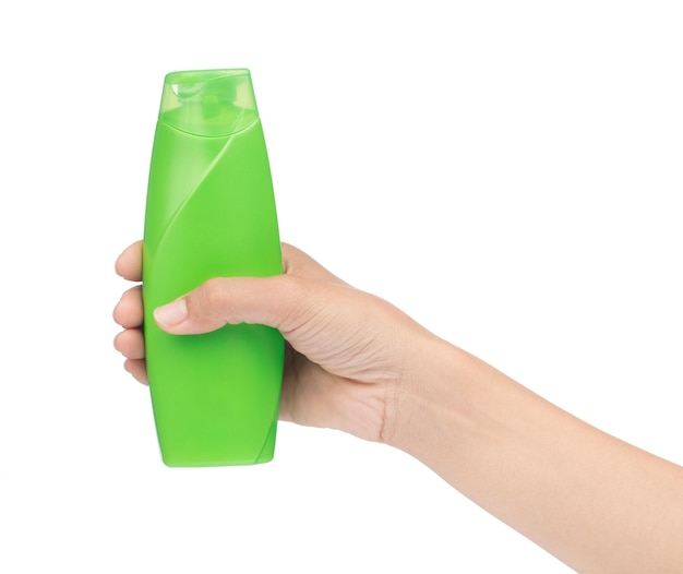 Hand holding green plastic bottle of shampoo isolated on white background