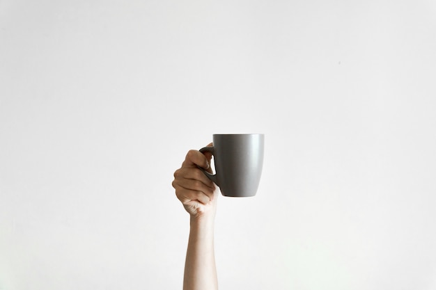 Hand holding a grey cupcoffe om white . sleepy morning. copyspace