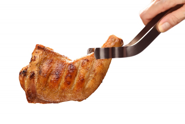 Hand holding grilled chicken thigh on white background