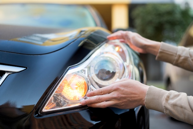 Hand holding headlight of dark car