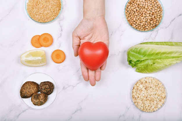 Photo hand holding heart among different foods