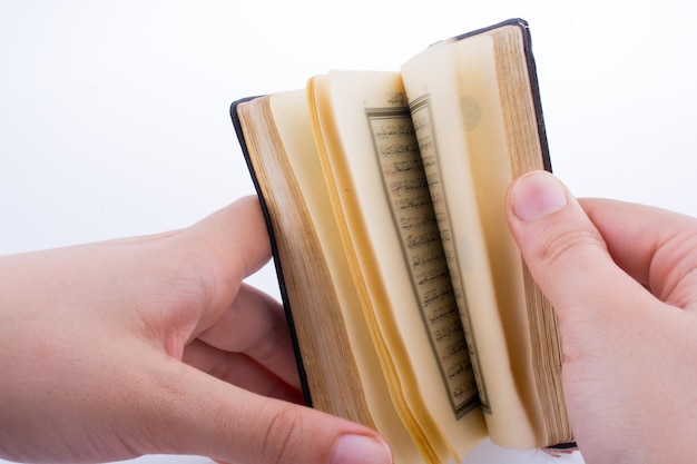 Hand holding The Holy Quran on a white background