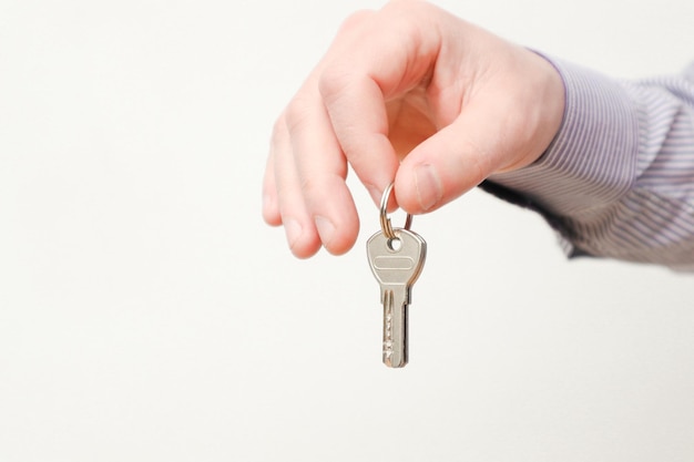 Hand holding house keys moving house relocation caucasian male hand holding key to house on white background copy space
