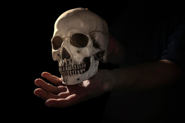 어두운 배경으로 인간의 두개골 머리를 들고 있는 손 무서운 두개골 할로윈 개념