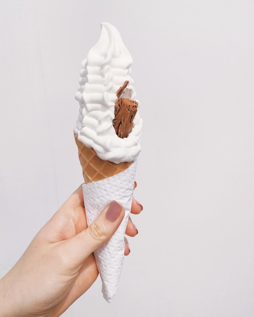 Photo hand holding ice cream cone against white background