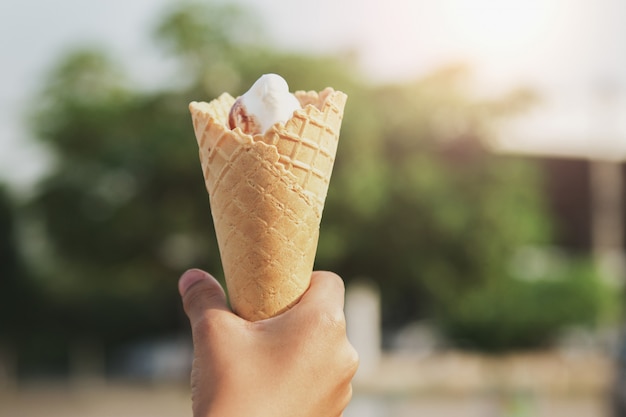 Hand holding ice cream cone in morning light