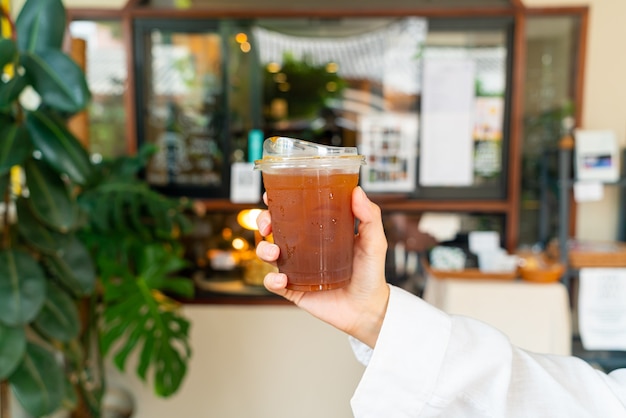 hand holding iced americano coffee in takeaway glass