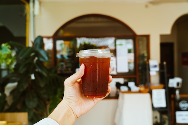 hand holding iced americano coffee in takeaway glass