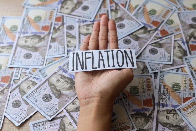 Hand holding Inflation text on background from dollar bills. Business and Inflation concept.