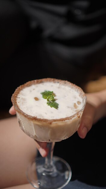 Foto mano che tiene il caffè irlandese con latte e rum e tiramisù con foglie di menta guarnire il mocktail superiore