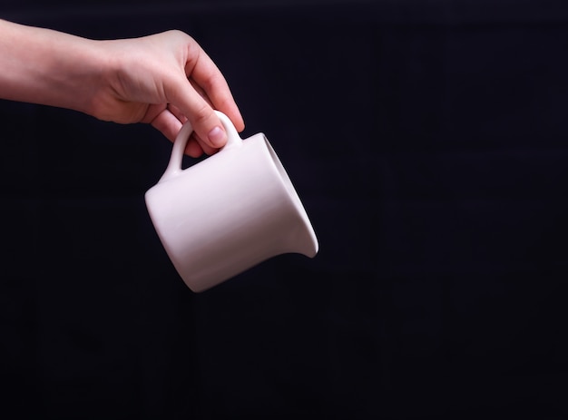 Hand holding jug on dark background