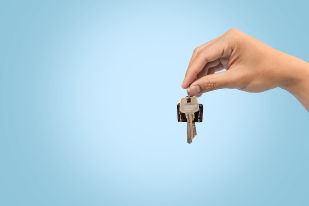 Hand holding keys blue background for refinance plan and real estate concept.