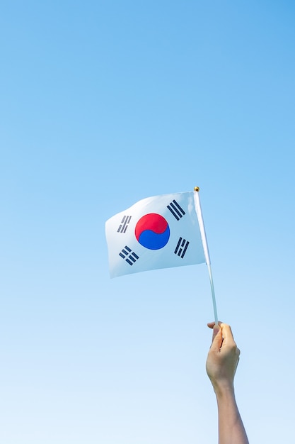 자연 배경에 한국 국기를 들고 손입니다. 건국, 개천절, 공휴일, 광복절 및 행복한 축하 컨셉