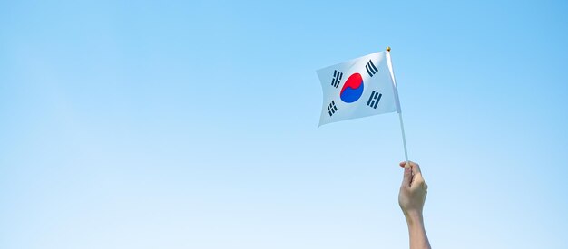 자연 배경에 태극기를 들고 있는 손 국립 재단 개천절 공휴일 광복절과 행복한 축하 개념