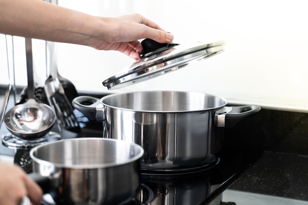 Hand holding lid above pan in kitchen