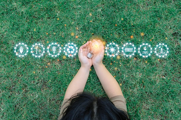 Hand holding light bulb in nature Sustainable energy sources concept with light bulb and plant