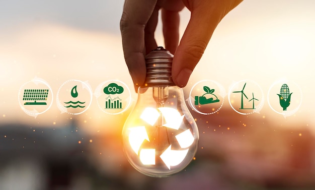 Hand holding light bulb with recycle symbol inside against with icons energy sources for renewable sustainable development