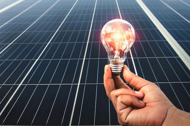 Hand holding light bulb with solar panel background