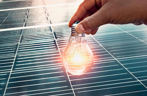 Hand holding lightbulb on solar panel concept clean energy in naturexA