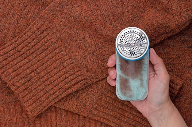 Hand holding lint remover with bin full of cutted lint