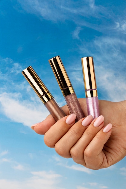 Photo hand holding lip balms with blue sky