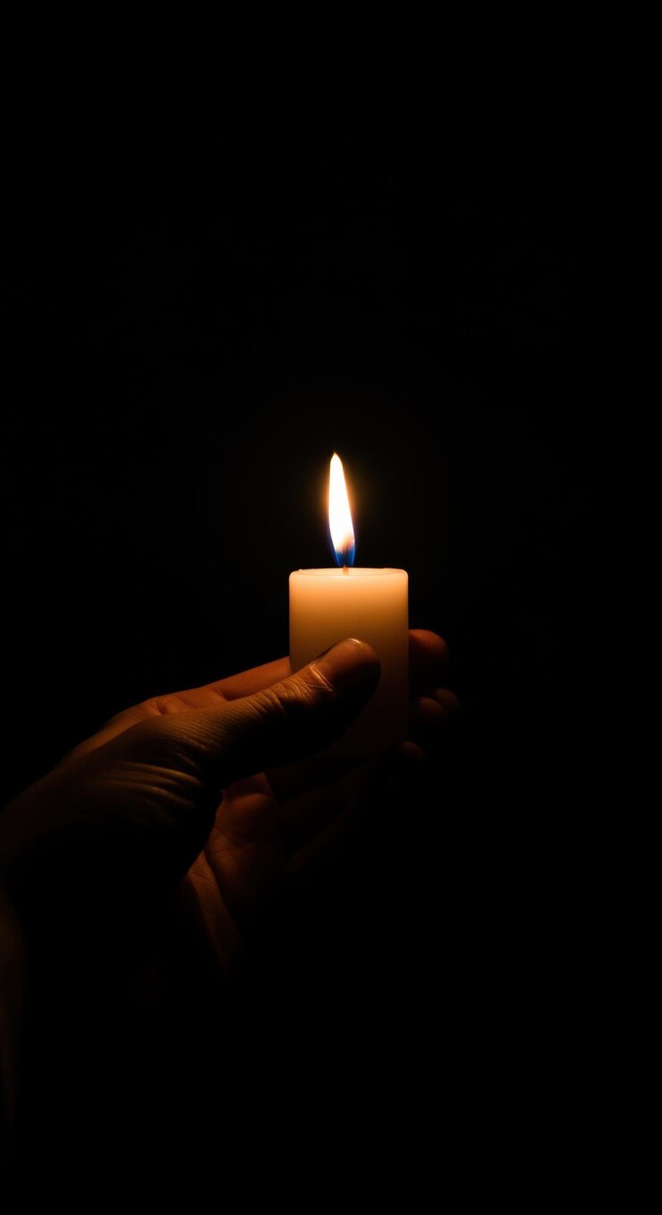 A Hand Holding a Lit Candle in the Dark A Symbol of Hope and Remembrance