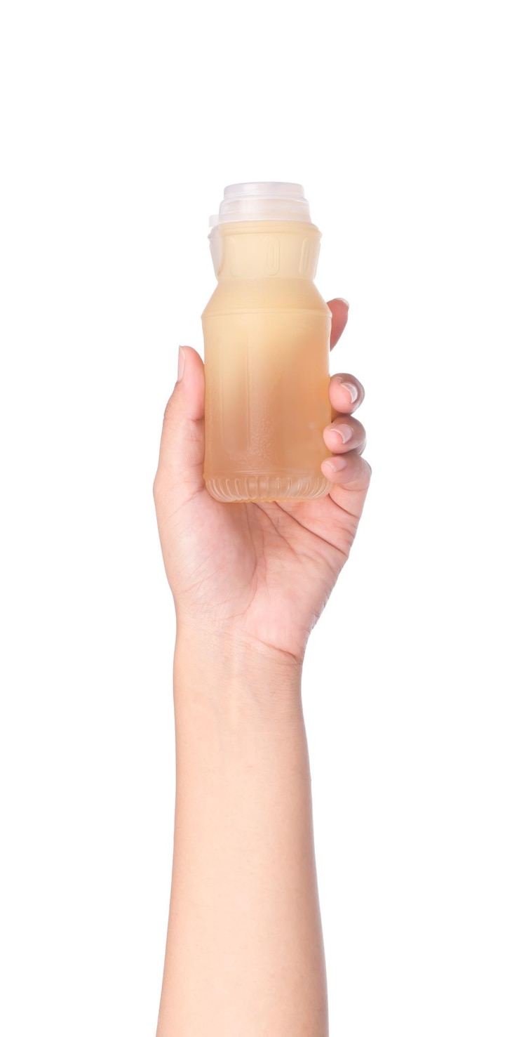 Photo hand holding longan juice into a bottle isolated on white background
